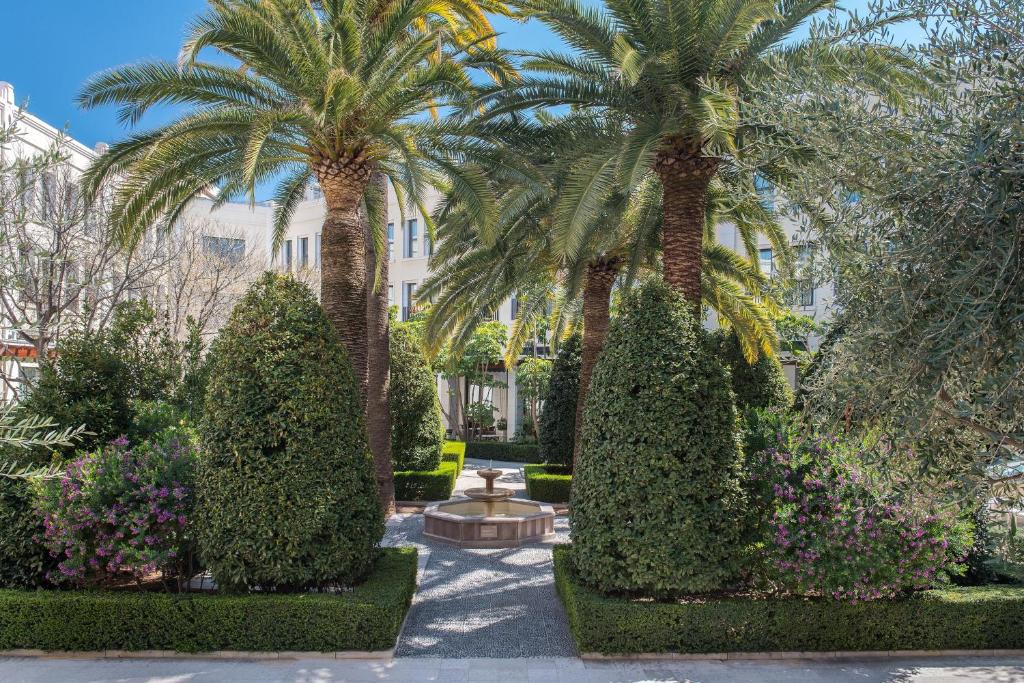 a garden with palm trees and flowers in front of a building at The Westin Valencia in Valencia