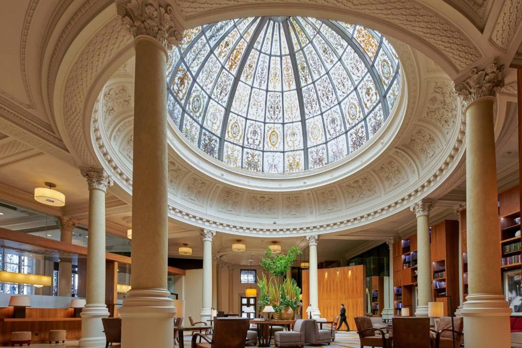 a library with a glass domed ceiling with tables and chairs at Threadneedles, Autograph Collection in London