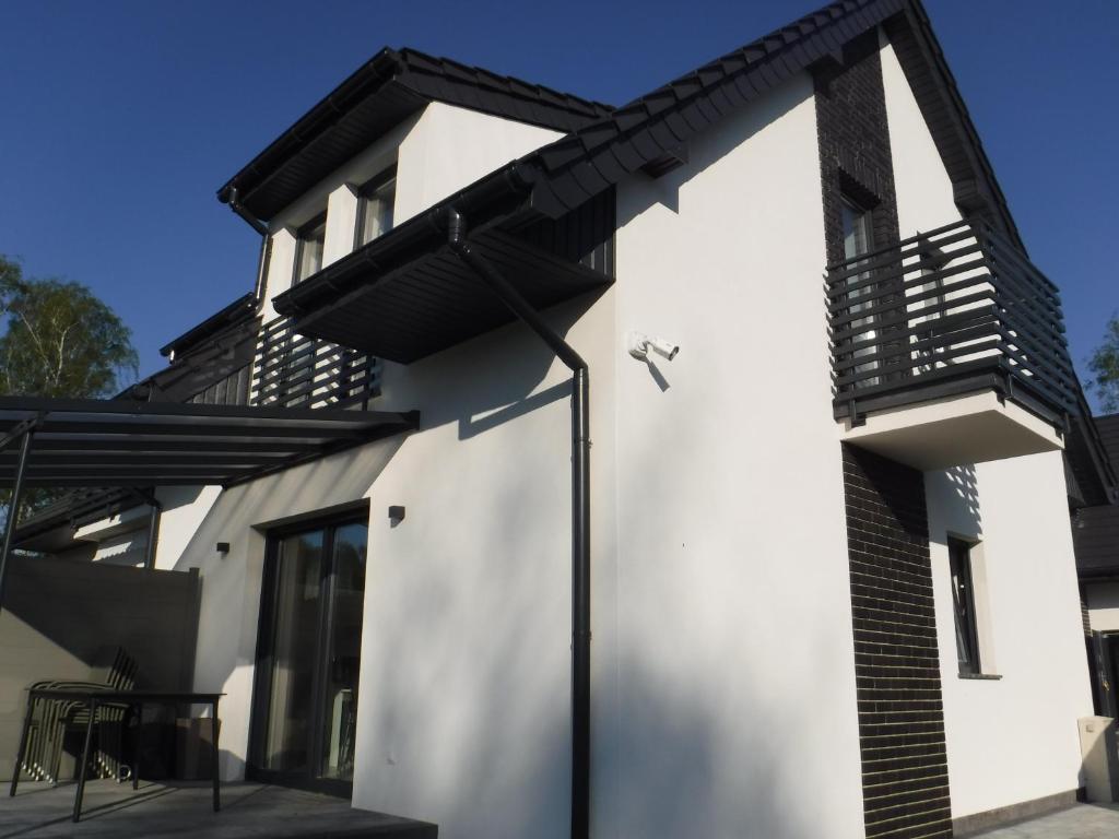 a white house with a black balcony at Villa Luis in Dziwnów