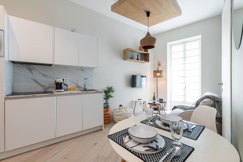 - une cuisine avec des placards blancs et une table avec de la vaisselle dans l'établissement Charming Central 1 Bdr, à Nice