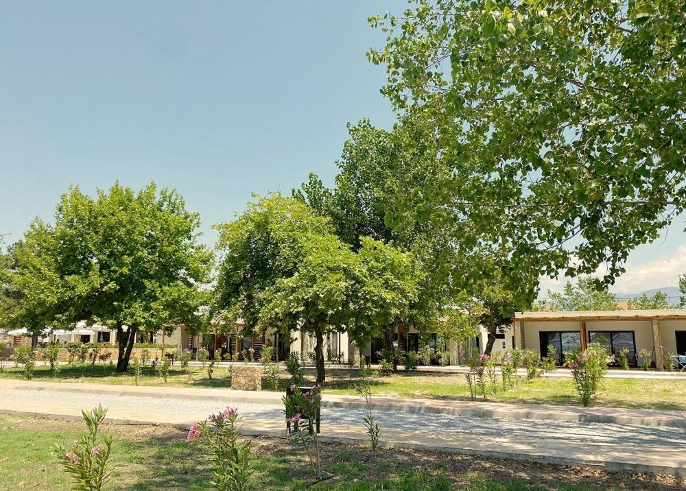 un parc avec des arbres et un banc devant un bâtiment dans l'établissement Mareleon Camping, à Ofrynio