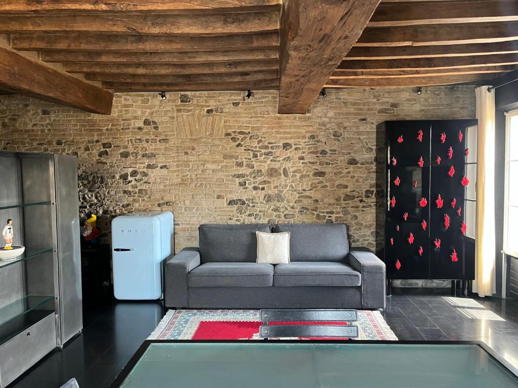 Ardesia Exclusive Apartament في بارما: غرفة معيشة مع أريكة وجدار من الطوب