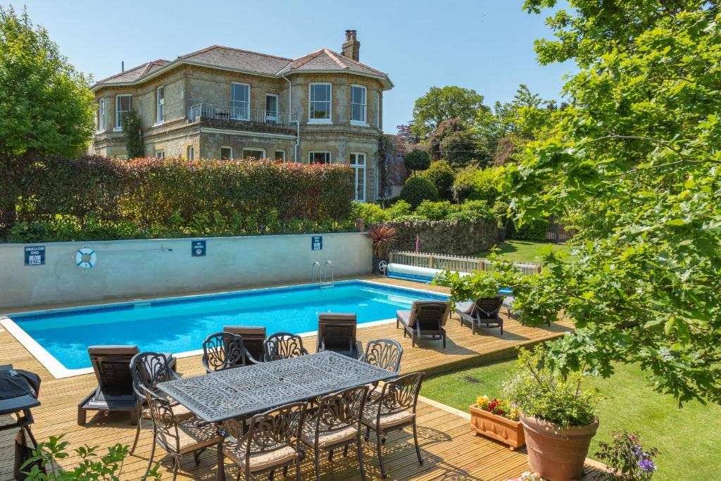 um pátio com uma mesa e cadeiras ao lado de uma piscina em Luccombe Villa Holiday Apartments em Shanklin