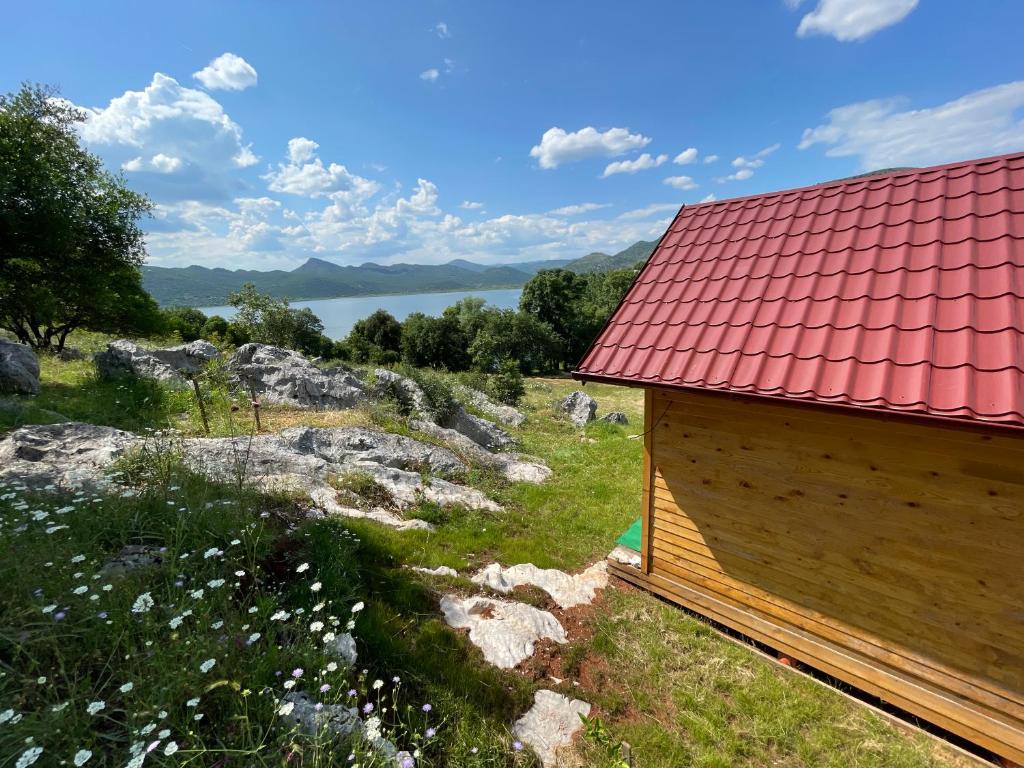 un edificio con techo rojo sobre un campo en Boljesestre Lake retreat, en Golubovci