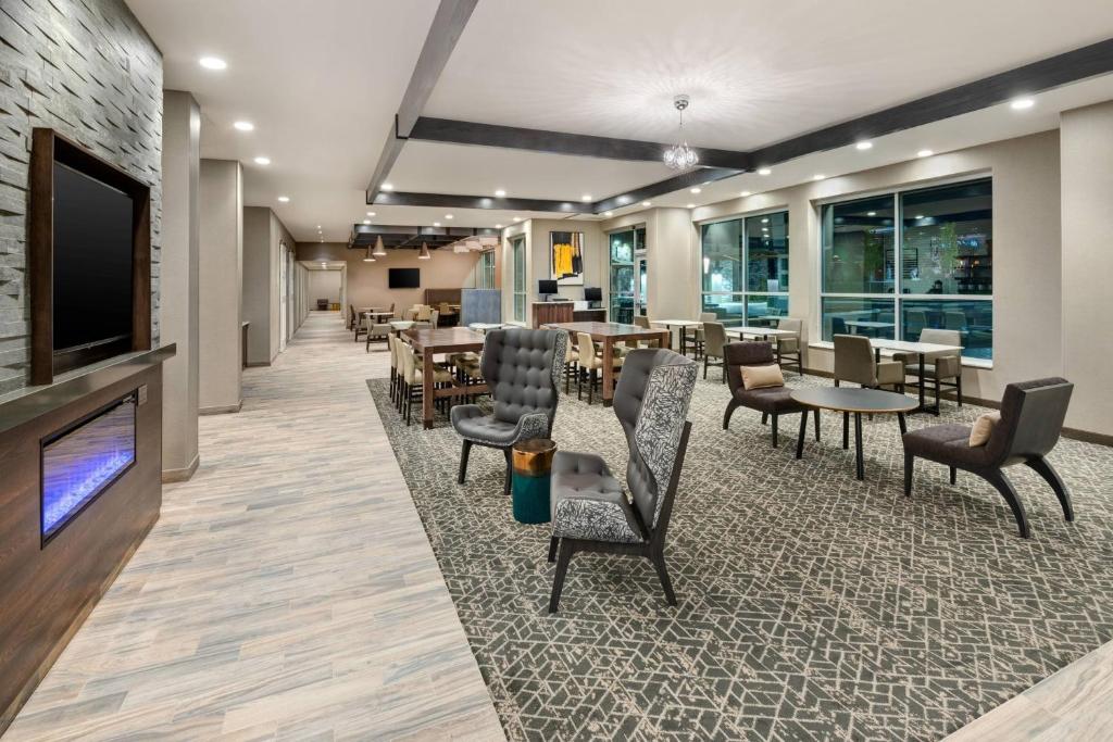 a waiting room with tables and chairs and a flat screen tv at Residence Inn by Marriott Indianapolis Keystone in Indianapolis