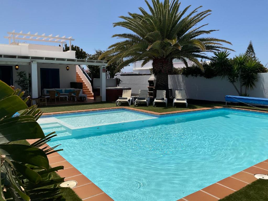 a swimming pool with a palm tree and a house at Villa Bonita in Playa Blanca