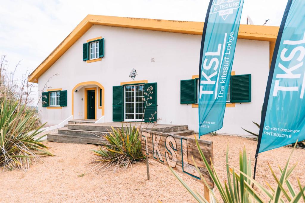 una casa con persiane verdi e cartelli di fronte ad essa di The Kitesurf Lodge a Casal do Narcizo