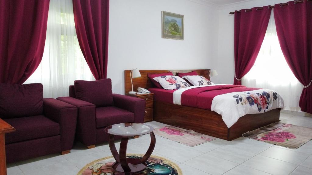 a bedroom with a bed and a couch and a chair at Charlestina Beach Resort in Ampeni