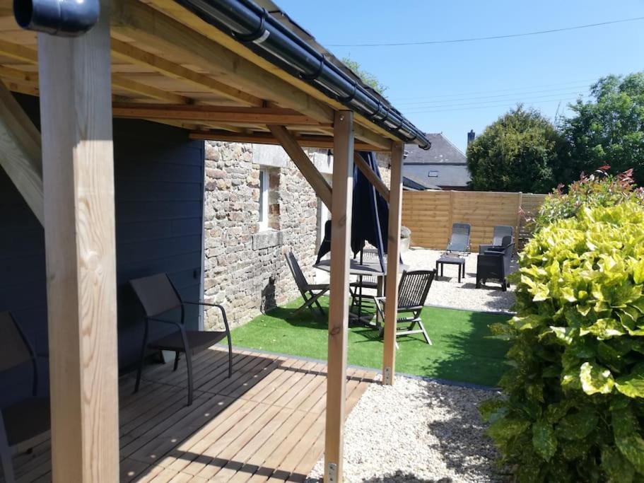 een patio met stoelen en een houten terras bij Charmante longère en pierres refaite à neuf in Moëlan-sur-Mer