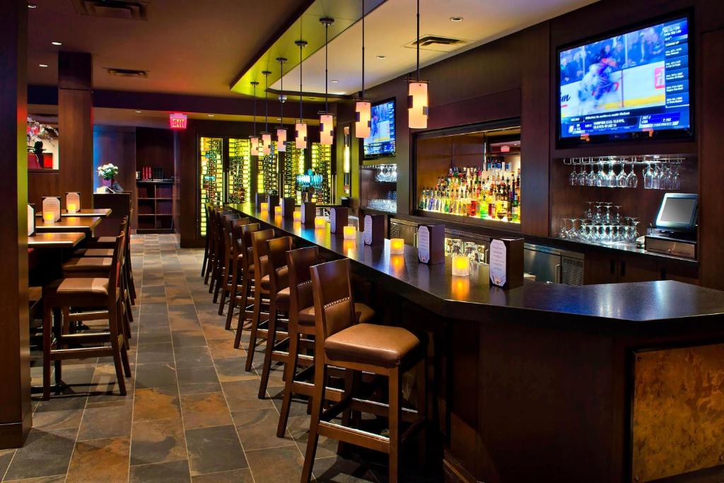 eine Bar in einem Restaurant mit Stühlen und einem TV in der Unterkunft Courtyard by Marriott Niagara Falls in Niagara Falls