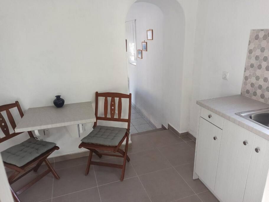 cocina con 2 sillas, mesa y nevera en Δίκλινο δωμάτιο Δονούσα με εξαιρετικό μπαλκόνι en Donoussa