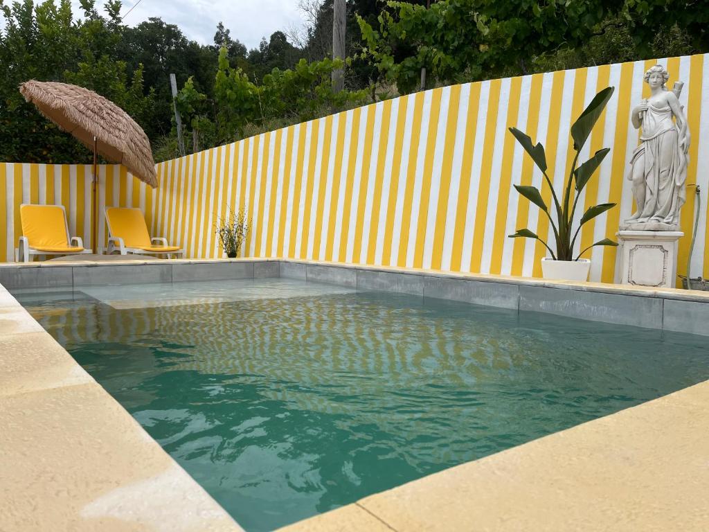 een zwembad met 2 stoelen en een gele muur bij Emiliadourohouse in Marco de Canavezes
