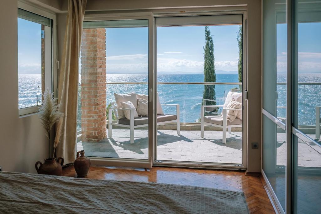 una camera da letto con vista sull'oceano attraverso porte scorrevoli in vetro di Villa Alenor Nessebar a Nesebar