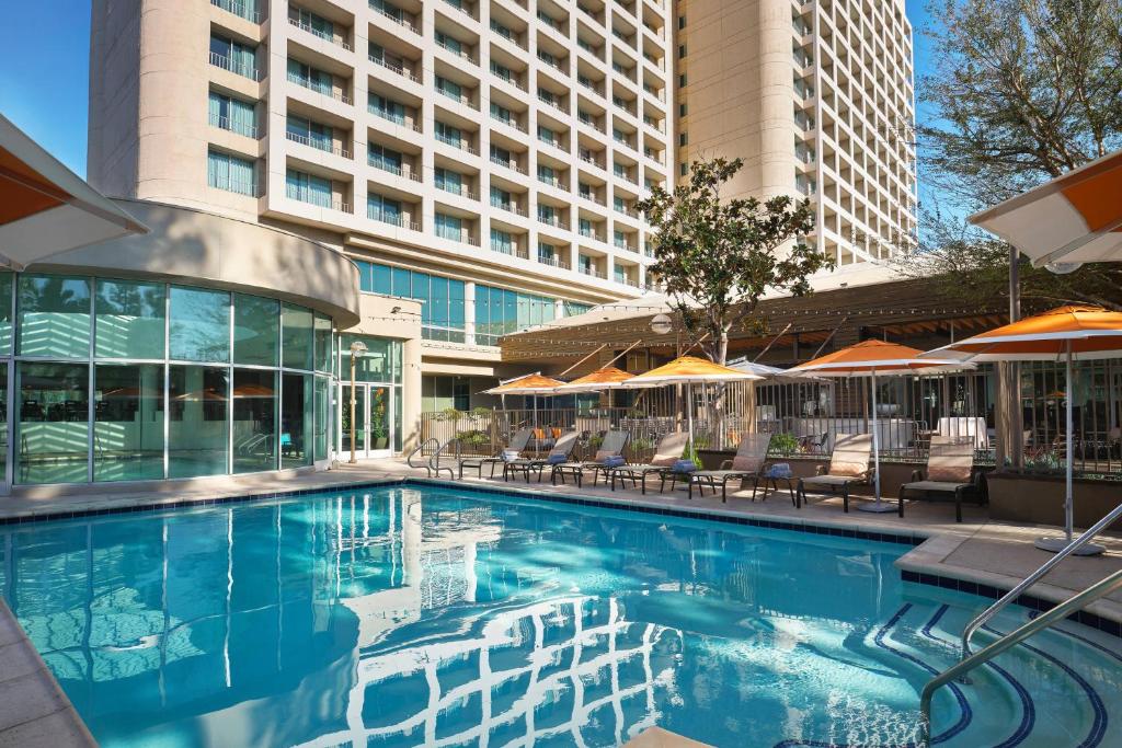 una piscina con sillas y sombrillas en un hotel en Warner Center Marriott Woodland Hills en Woodland Hills