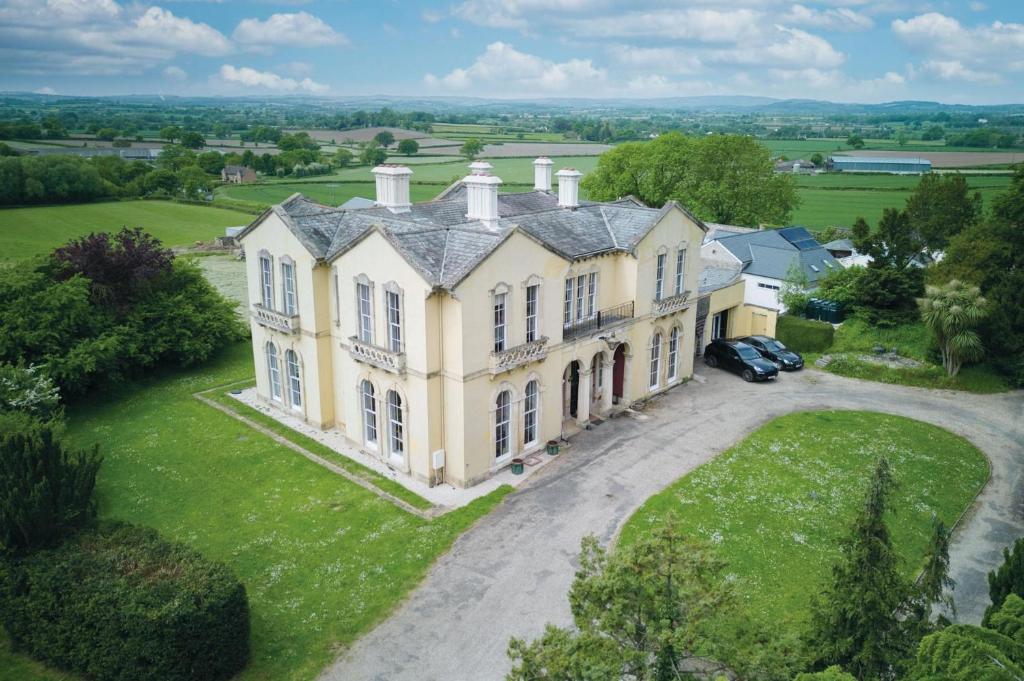 an aerial view of a large yellow house with a driveway at Rumwell Park - 8 Bedroom Manor House- Taunton in Taunton