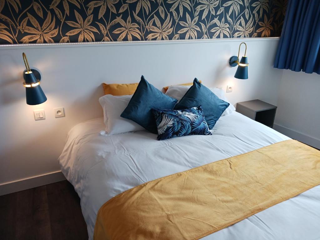 a bed with blue pillows on it in a bedroom at The Originals Access, Hôtel Millau Sud in LʼHospitalet-du-Larzac