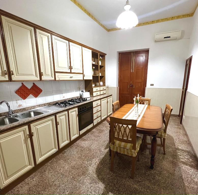 - une cuisine avec une table en bois, des chaises et un évier dans l'établissement Casa Centamore, à Biancavilla