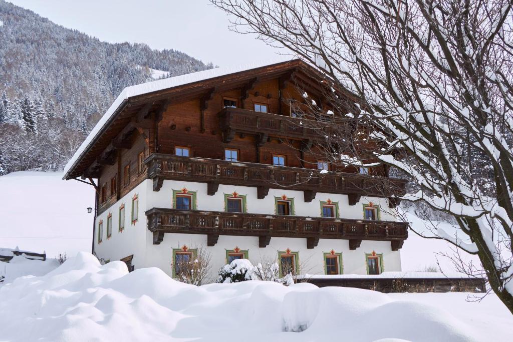 un edificio cubierto de nieve con nieve alrededor en Hinterauerhof, en Matrei in Osttirol