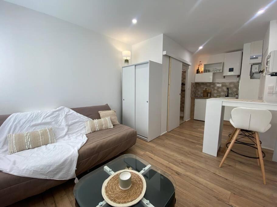 un salon avec un canapé et une table et une cuisine dans l'établissement Mon petit studio à la mer, à Gruissan