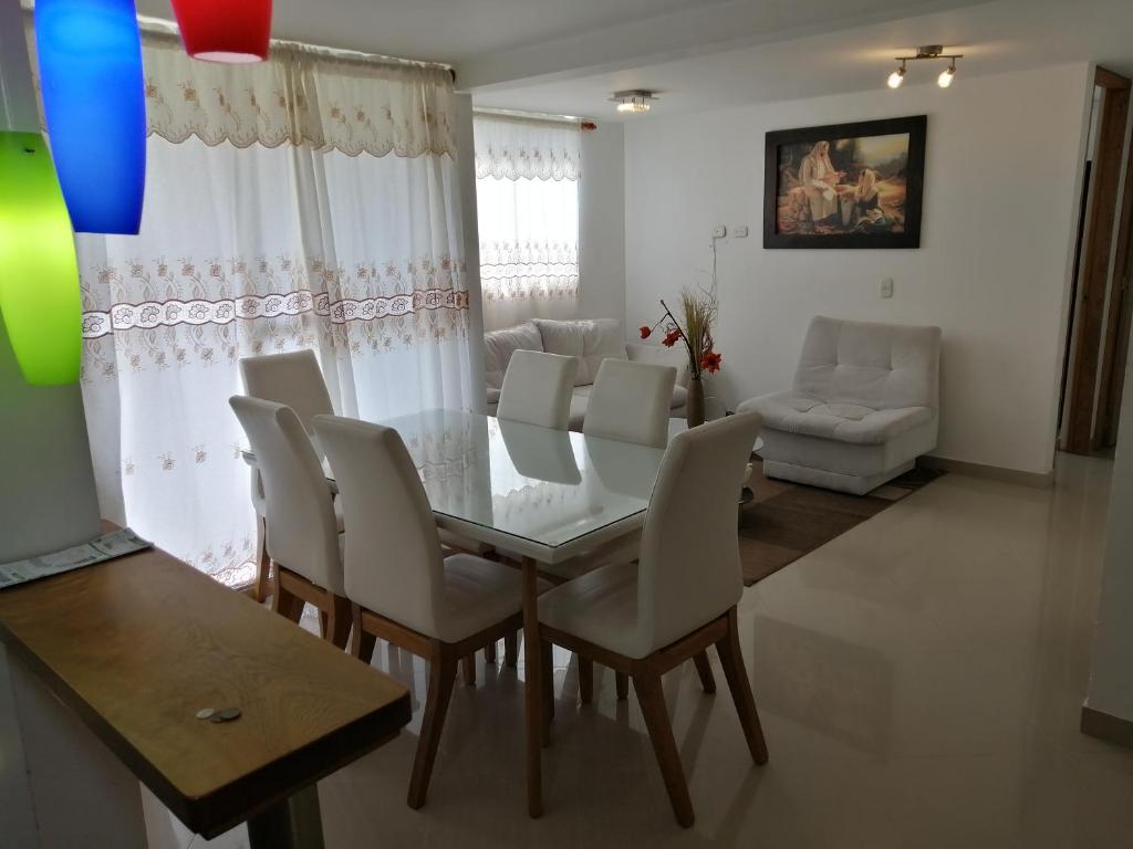 a dining room with a glass table and white chairs at Lindo Apartamento en alquiler in Rionegro