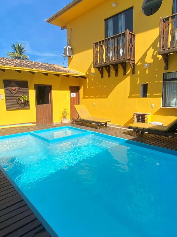 a swimming pool in front of a yellow house at Pousada Maravilha de Paraty in Paraty