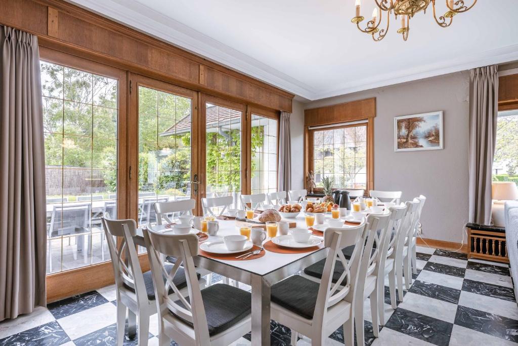 - une salle à manger avec une table, des chaises et des fenêtres dans l'établissement Villa Dolce Vita, à La Panne