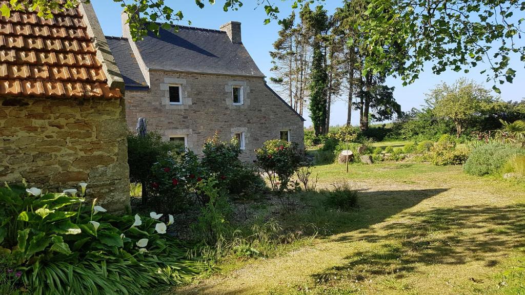 an old stone house in a garden with flowers at fermette in Plounévez-Lochrist