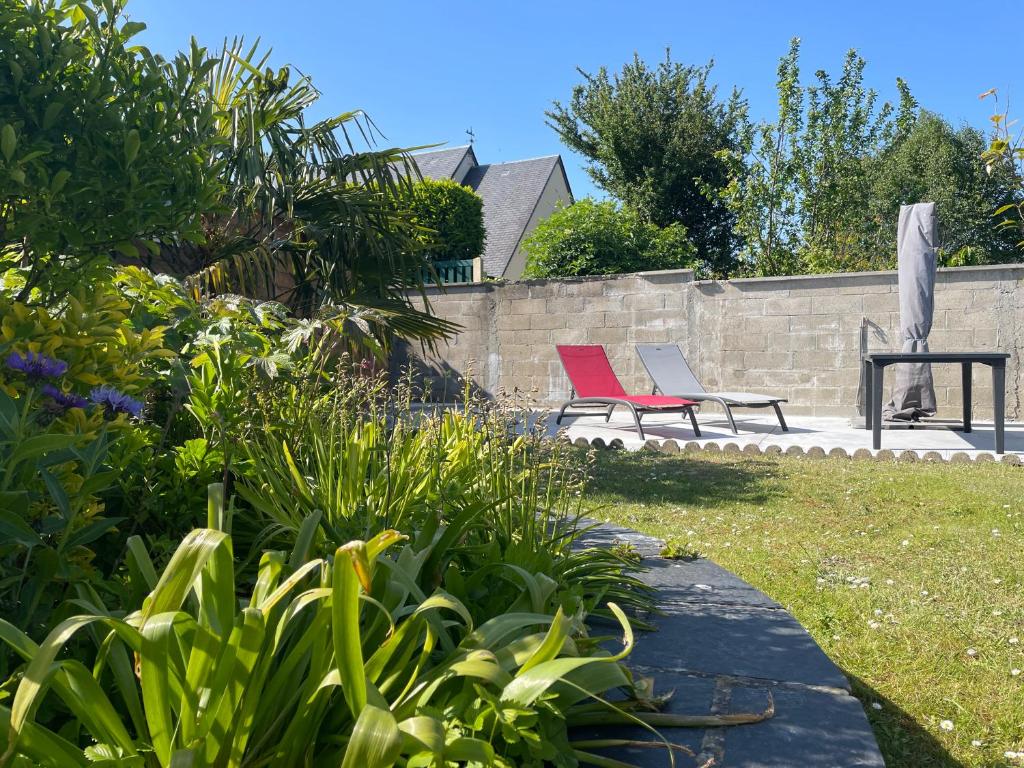 two chairs sitting in a garden next to a wall at La Renaissance in Bayeux