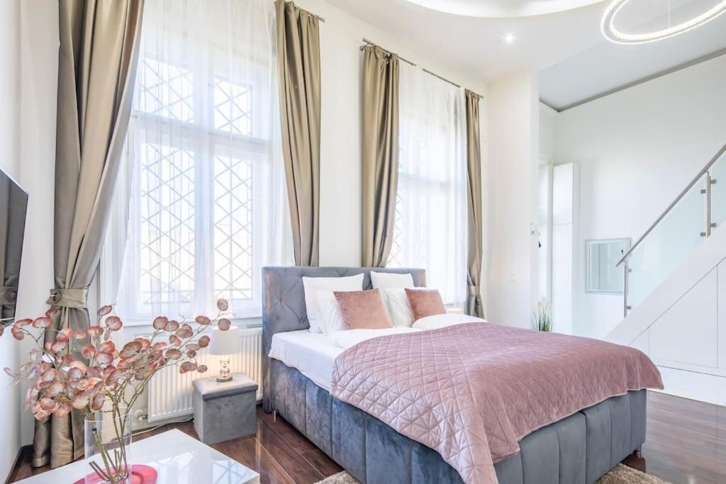 1 dormitorio con 1 cama en una habitación con ventanas en Opera Luxury Studio Apartment, en Budapest