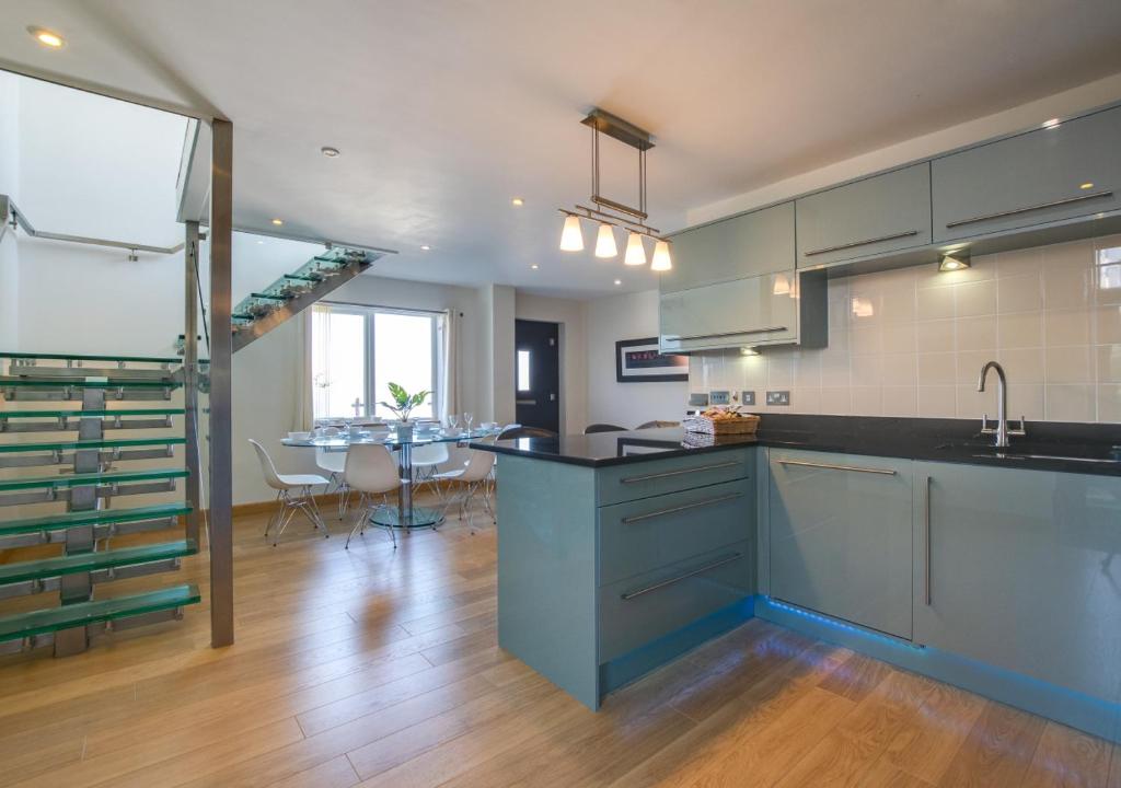 uma cozinha com armários azuis e uma sala de jantar em Tuppence View em Swanage
