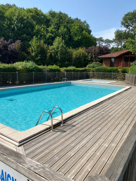 una gran piscina con terraza de madera junto a en La petite gravière Océane, en Messanges