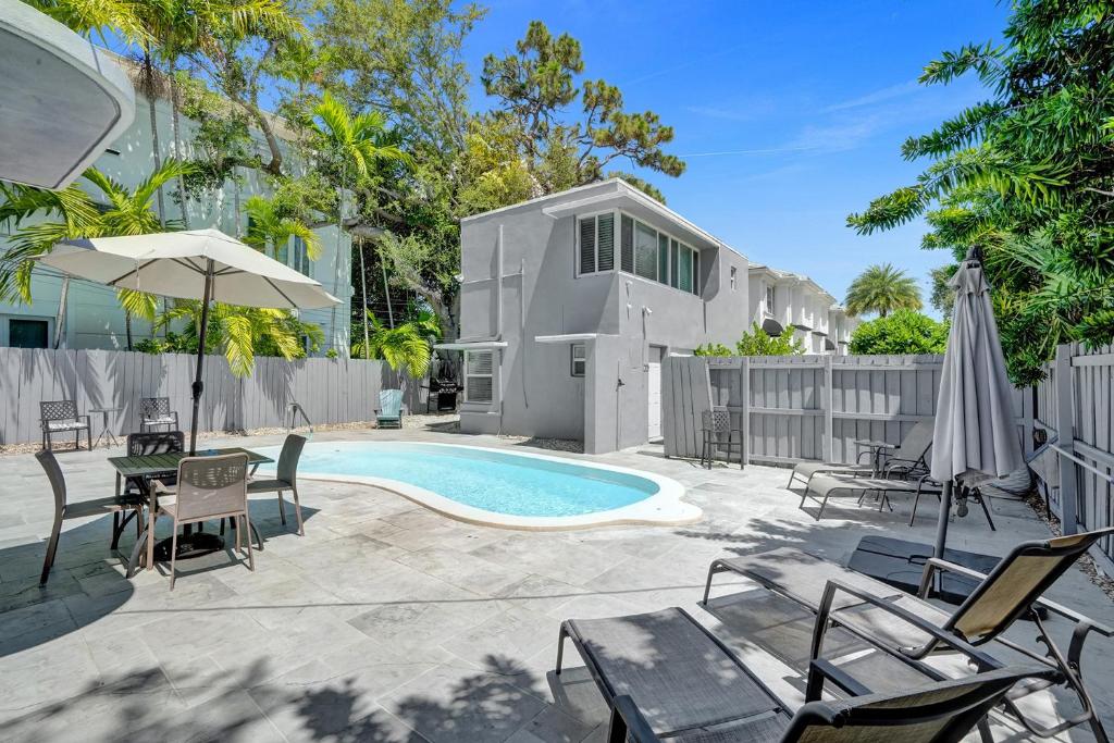 einen Hinterhof mit Pool und Stühlen und ein Haus in der Unterkunft Oasis by Las Olas Lux Getaway in Fort Lauderdale