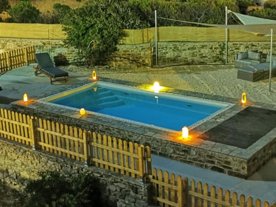 a swimming pool with candles in a backyard with a fence at Dream Inn Paros, private pool in Sarakíniko