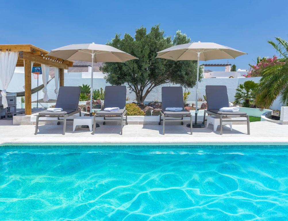 una piscina con due sedie e ombrelloni di Villa Olive Tree a Playa Blanca