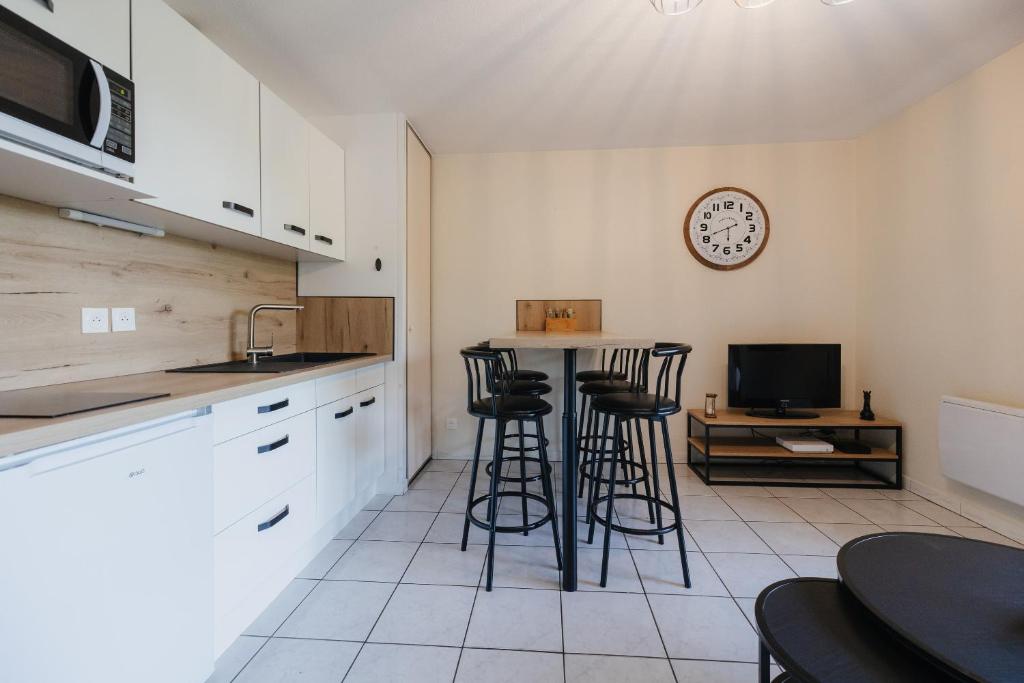 a kitchen with bar stools and a clock on the wall at Bel appartement 6 couchages au plan d&#39;eau d&#39;Embrun in Embrun