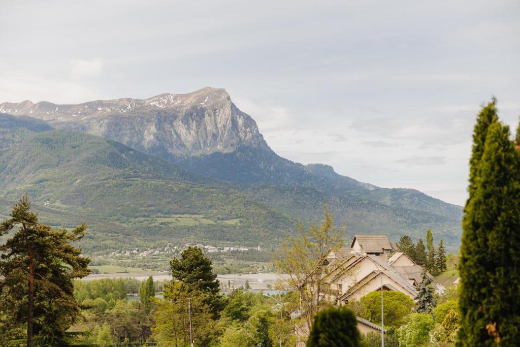 a mountain in the distance with a house in the foreground at Bel appartement 6 couchages au plan d&#39;eau d&#39;Embrun in Embrun