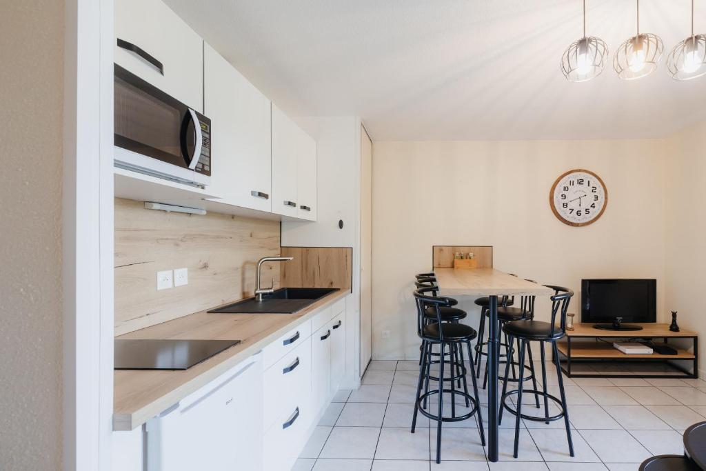 a kitchen with white cabinets and bar stools at Bel appartement 6 couchages au plan d&#39;eau d&#39;Embrun in Embrun
