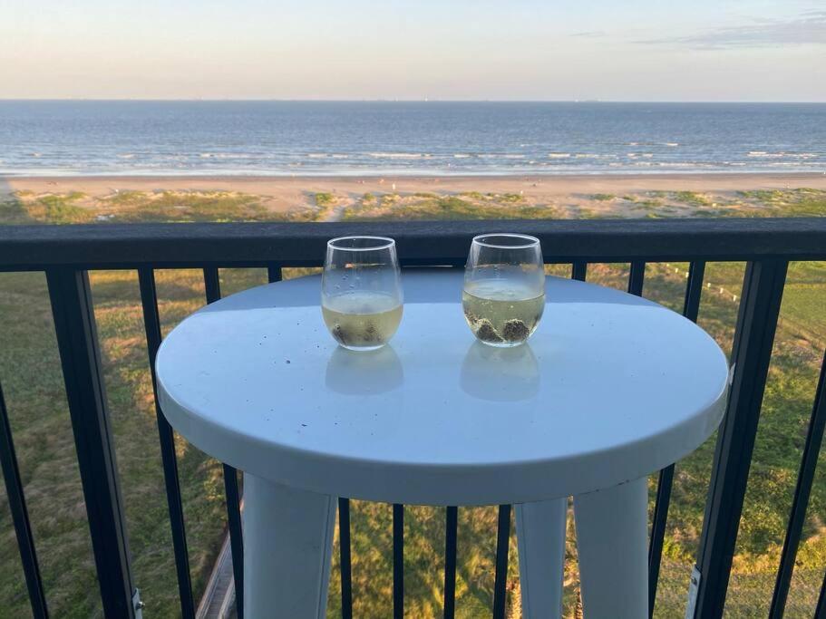 a white table with two wine glasses on a balcony at Beachfront Islander East Studio in Galveston