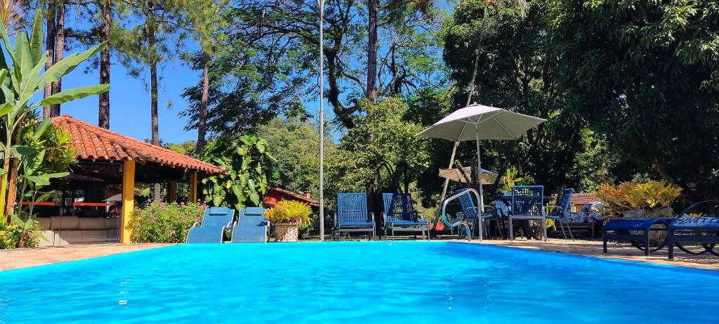 a large blue swimming pool with an umbrella at Pousada Villa Luna in Penedo
