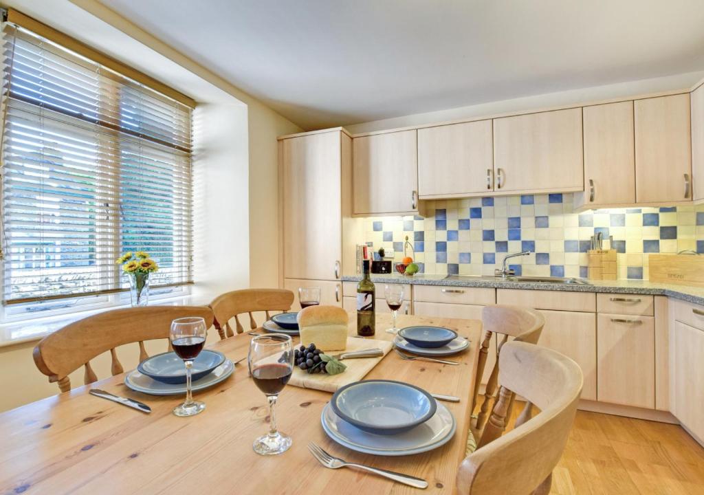 a kitchen with a wooden table with glasses of wine at Elterwater Apartment in Bowness-on-Windermere