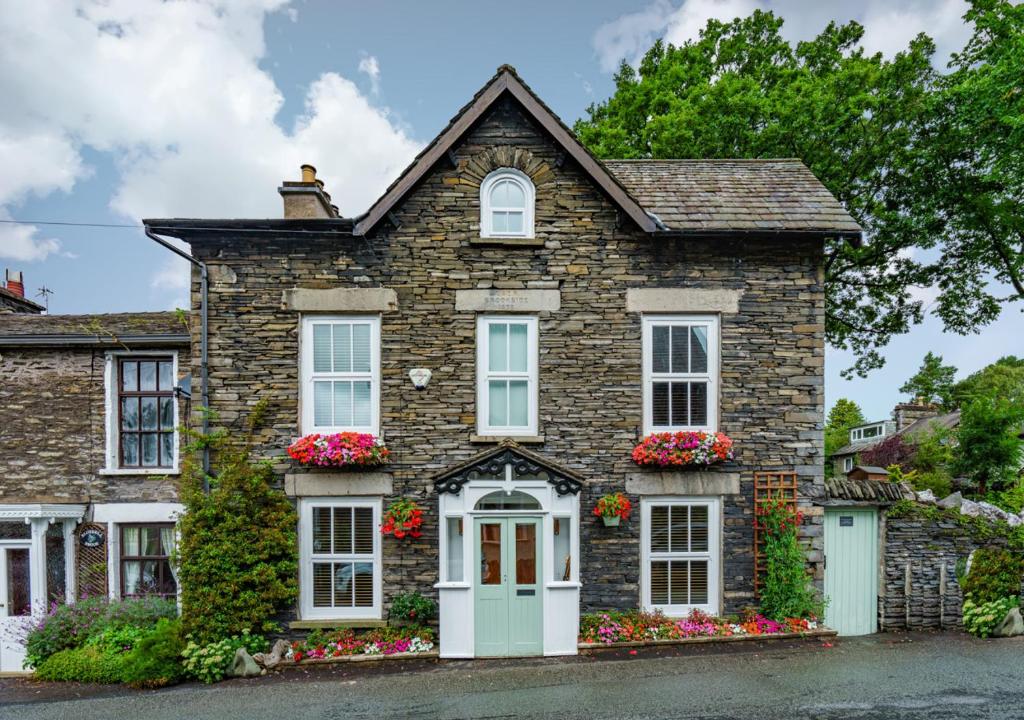 a brick house with white windows and flowers at Brookside Cottage in Windermere