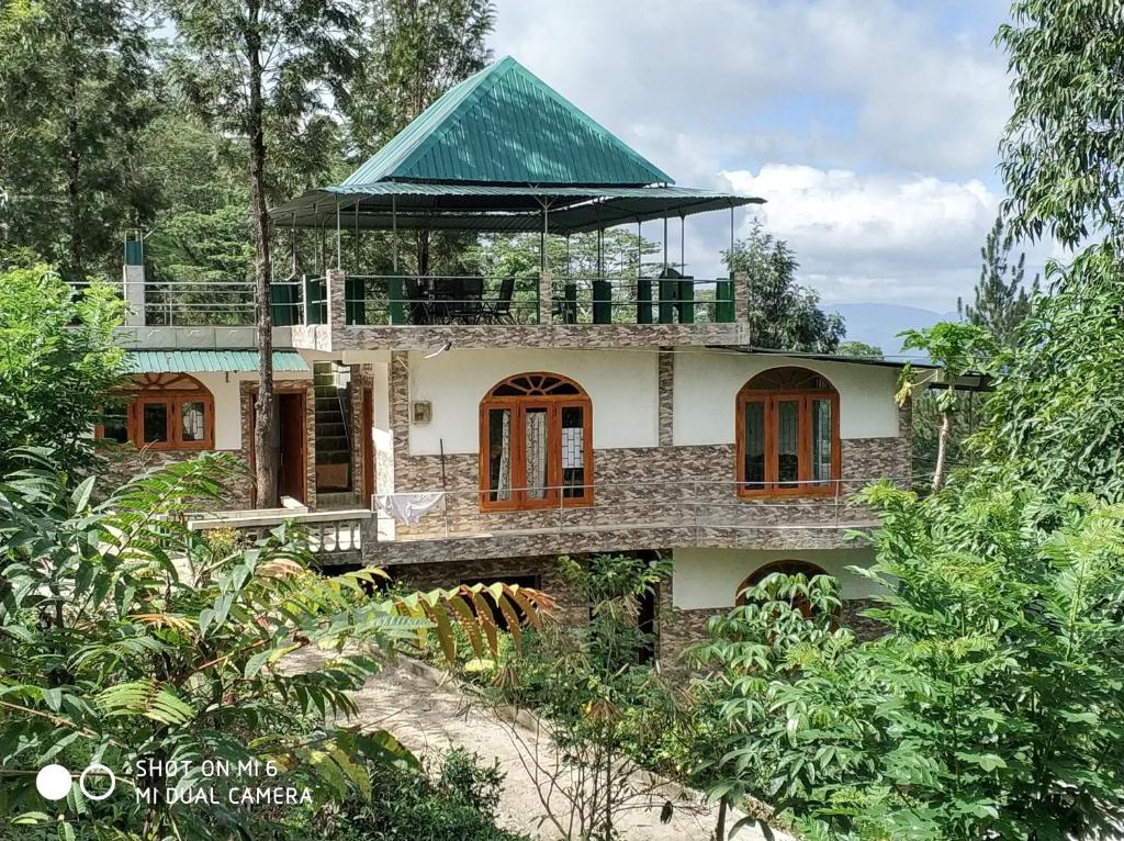 een huis met een groen dak in het bos bij Rohana Estate Lodging & Camping in Kandy