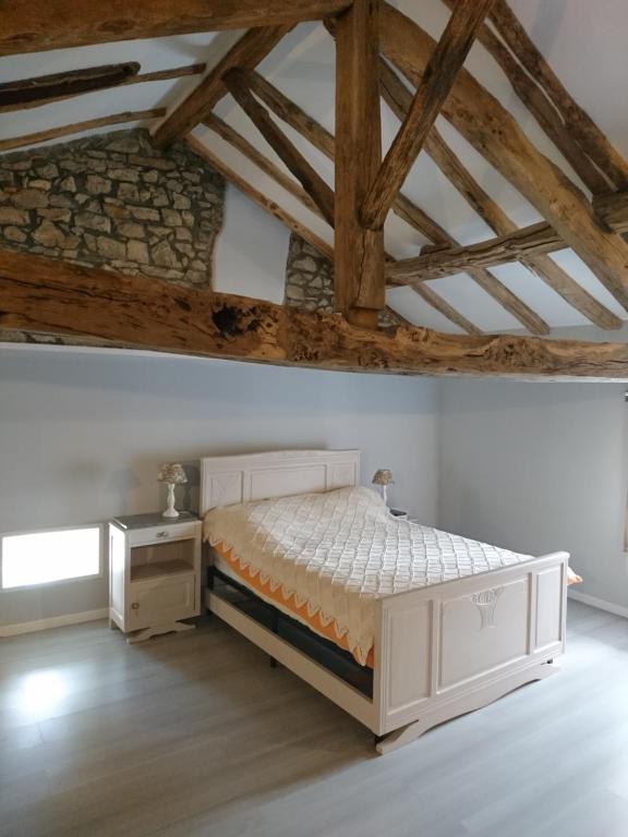a bedroom with a white bed and a wooden ceiling at La Croisée Des Chemins in Maisonnais-sur-Tardoire