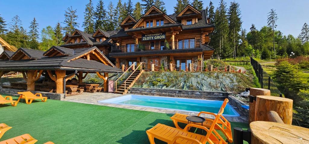 a log house with a swimming pool in front of it at Apartamenty Złoty Groń in Istebna