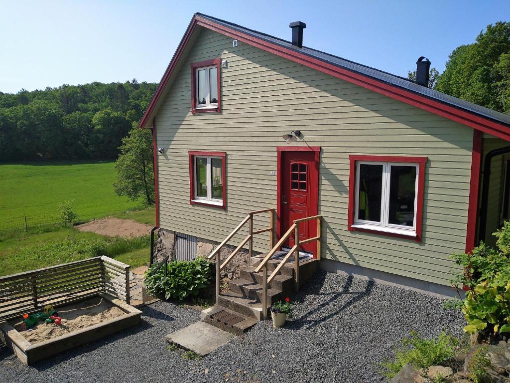 una pequeña casa verde con una puerta roja y escaleras en Villa Ulvatorp nära Varberg och Ullared, en Veddige