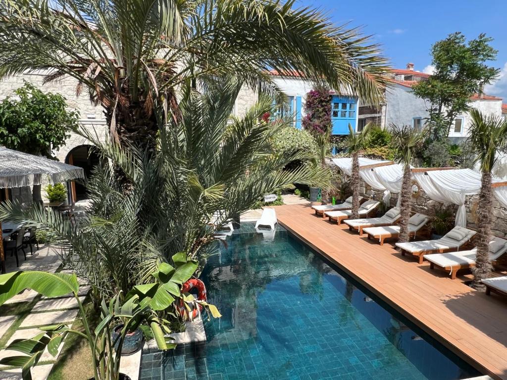 a swimming pool with lounge chairs and palm trees at The ABC Hotel in Alaçatı