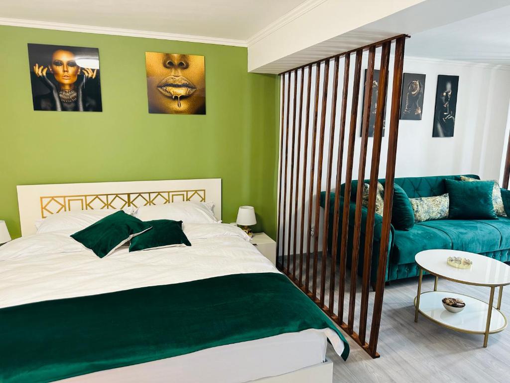 Luxor Apartament Sibiu في سيبيو: غرفة نوم بجدران خضراء وسرير واريكة