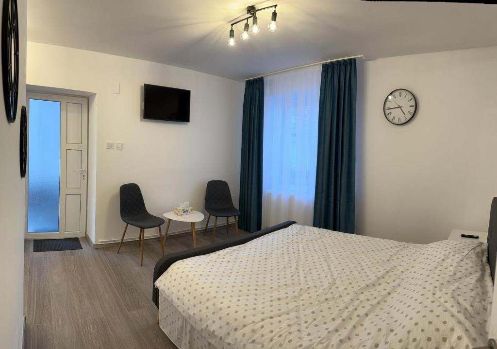 a bedroom with a bed and two chairs and a clock at Easy Living Apartments - Old Town in Braşov
