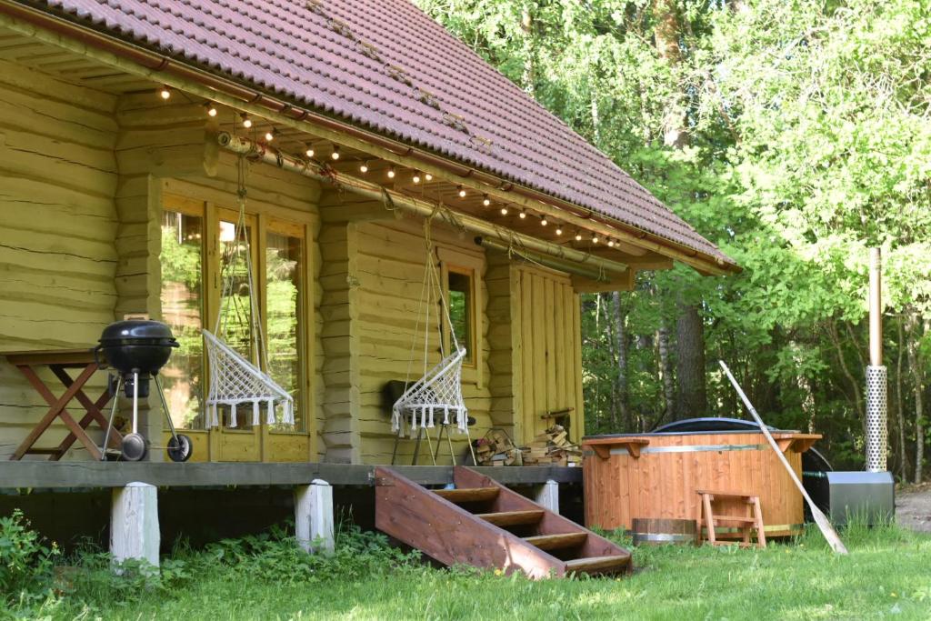 una piccola casa gialla con griglia e vasca di Quiet Log House, Vaikne palkmaja, Kevadekuulutaja, Harbinger of spring a Rannaküla
