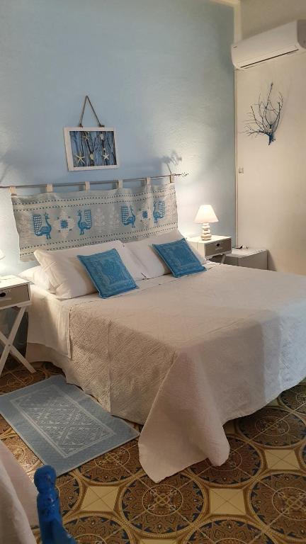 1 dormitorio con 1 cama blanca grande con almohadas azules en 4 stagioni en Villasimius